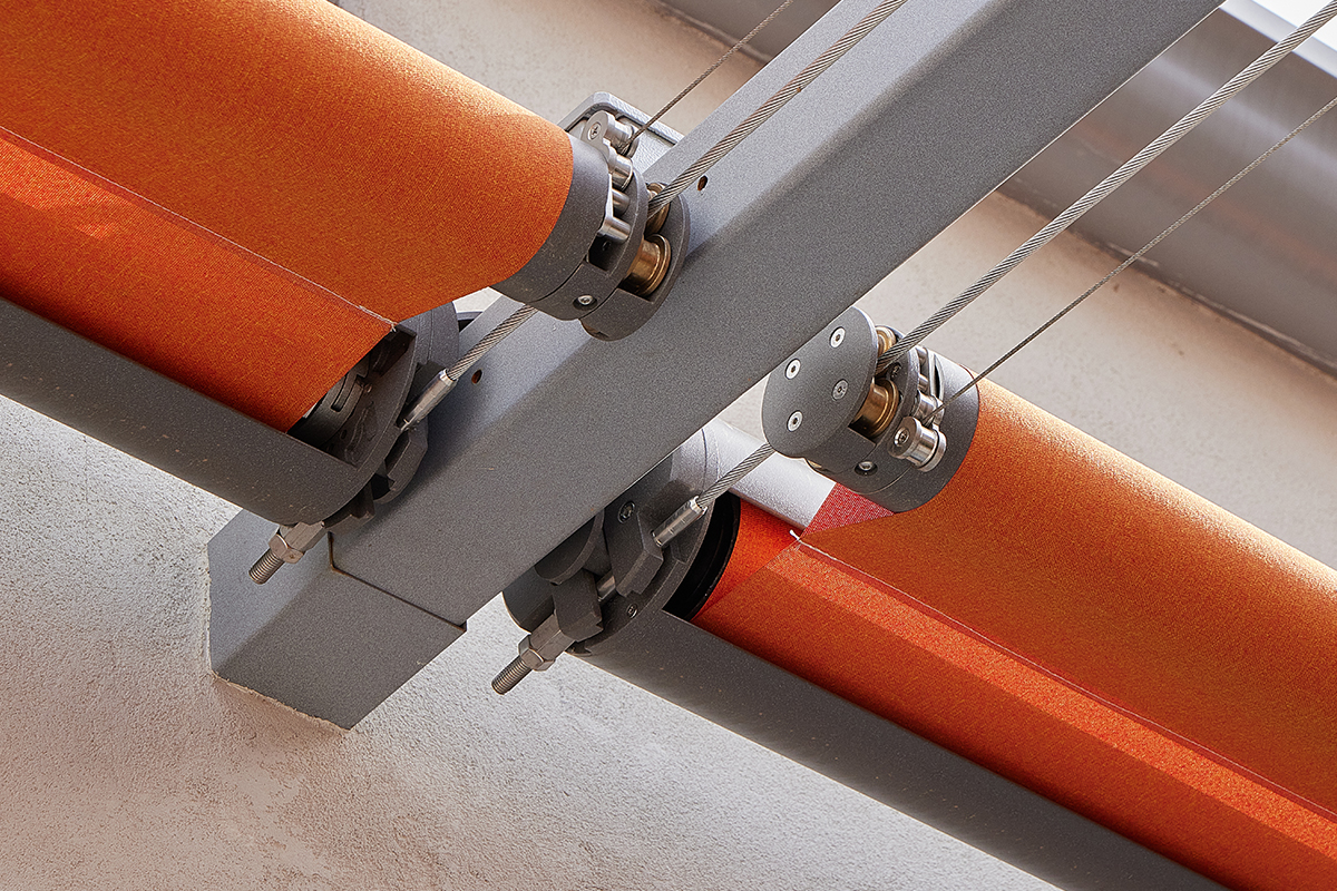 Dettaglio dell'ingranaggio che regge il tessuto Starscreen arancione per schermature solari e privacy